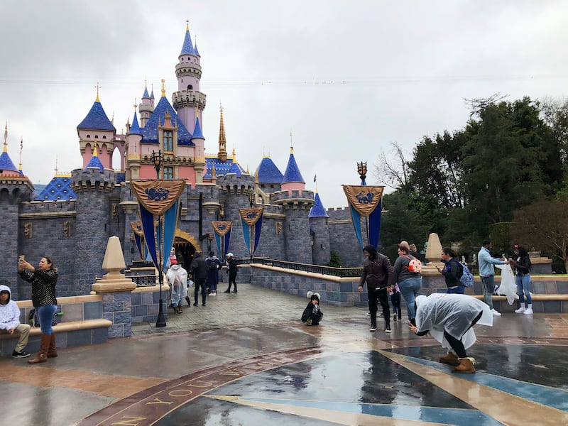 In this March 13, 2020 file photo, visitors take photos at Disneyland in Anaheim, Calif., the last day the park was open due to the COVID-19 pandemic