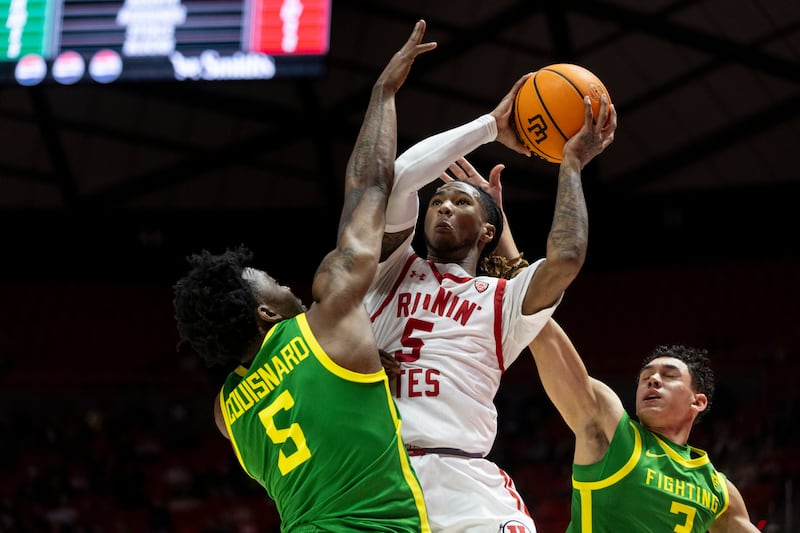 Utah Utes guard, Deivon Smith (5) jumps for a basket against Oregon Ducks guard, Jermaine Couisnard (5) and guard Jackson Shelstad (3) at the Huntsman Center in Salt Lake City on Jan. 21, 2024. The Utes won 80-77.