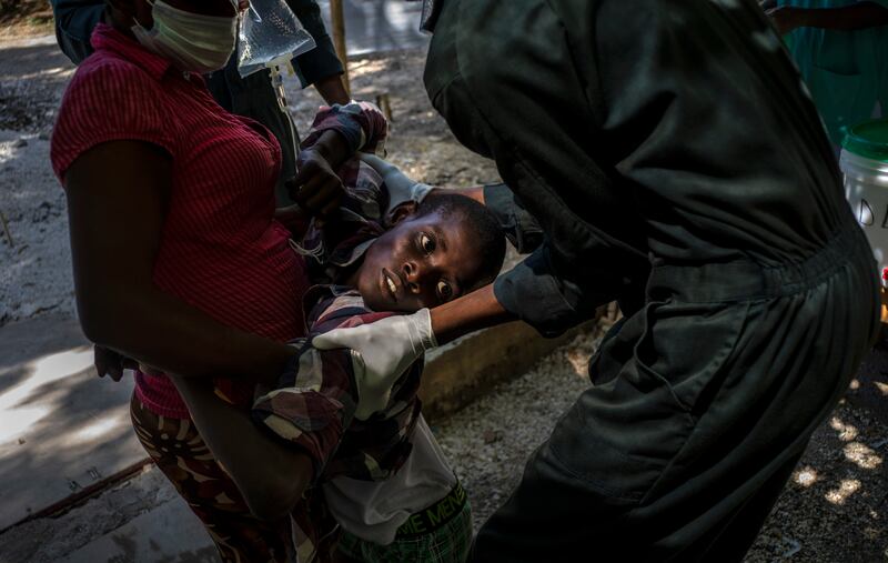 A youth suffering cholera symptoms is helped upon arrival at a clinic run by Doctors Without Borders in Port-au-Prince, Haiti.