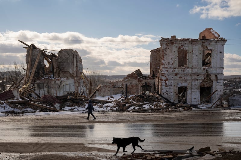 A woman walks by a building destroyed by a Russian strike in Kupiansk, Ukraine, Monday, Feb. 20, 2023.