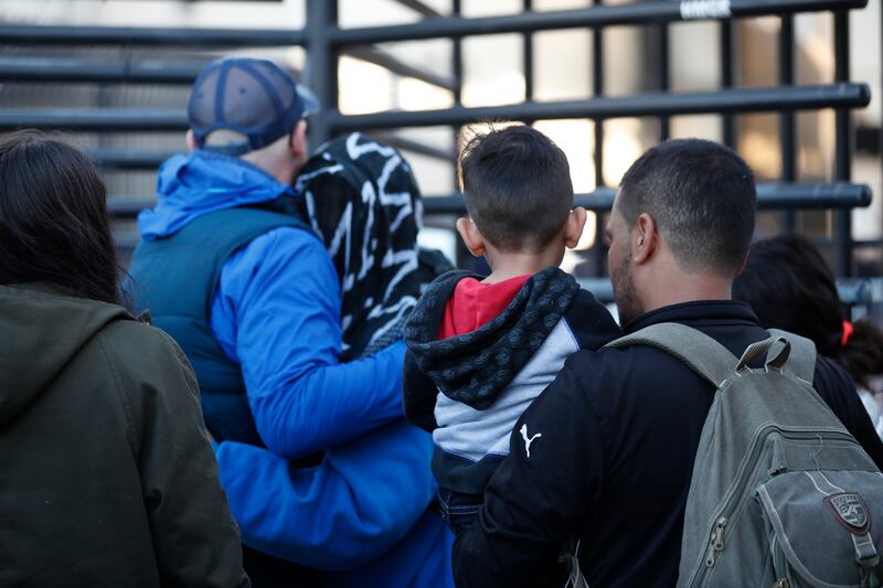 In this Dec. 18, 2018 photo, Honduran asylum seekers enter the U.S. at San Diego’s Otay Mesa port of entry, as seen from Tijuana, Mexico.