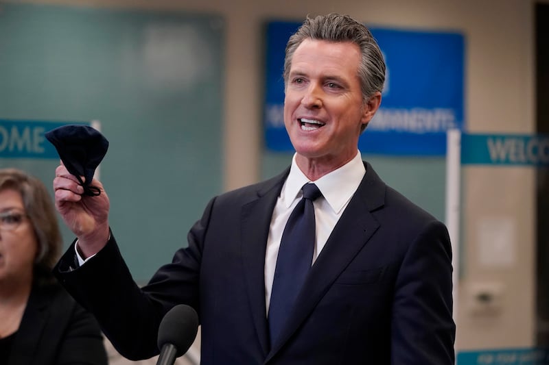 California Gov. Gavin Newsom holds a face mask while speaking at a news conference in Oakland, California.