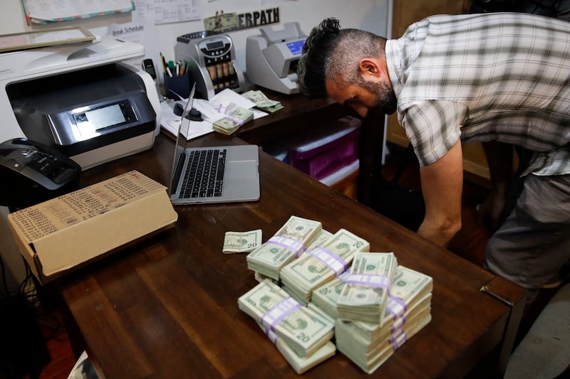 FILE - In this June 27, 2017, photo, bundles of $20 bills are placed on a table as Jerred Kiloh, owner of the Higher Path medical marijuana dispensary, prepares a trip to Los Angeles City Hall to pay his monthly tax payment in cash in Los Angeles.