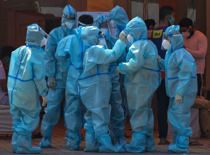 Health workers and volunteers in personal protective suits wait to receive patients outside a COVID-19 hospital that was set up at a Sikh Gurdwara in New Delhi, India, Monday, May 10, 2021.