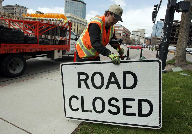Utah Barricade's Clifford Sweat places road signs on State Street that will be used to direct traffic during the Salt Lake City Marathon in Salt Lake City.