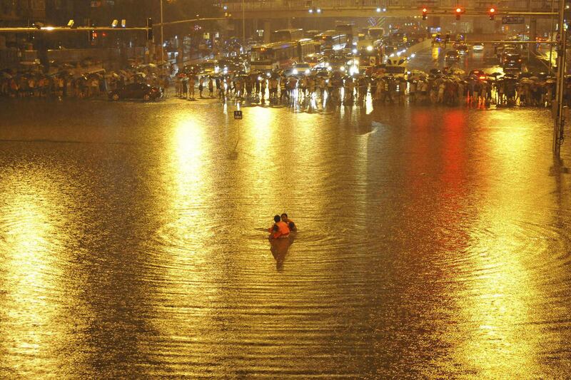 In this Saturday, July 21, 2012 photo, people watch as rescuers search for victims near a flooded underpass after heavy rains in Beijing. Residents impatient for official updates compiled their own death tolls Thursday, July 26, 2012, for last weekend's m