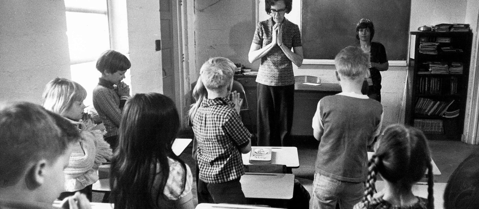 Volunteer classroom aid Rose Snuffler leads a prayer for students at Faith Gospel Tabernacle Elementary School