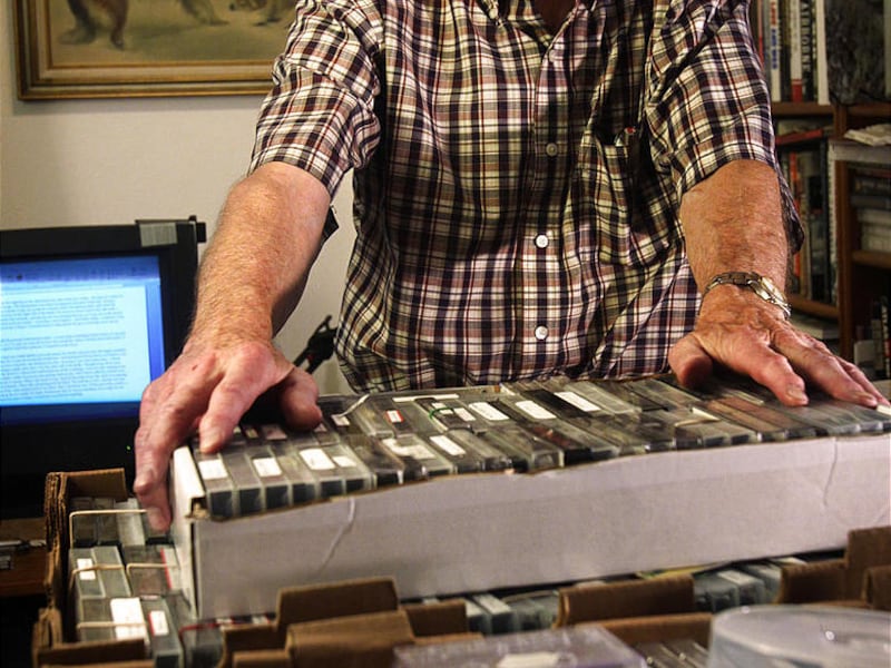 Don Norton stands next to a collection of taped interviews with veterans which he has been transcribing at his home.
