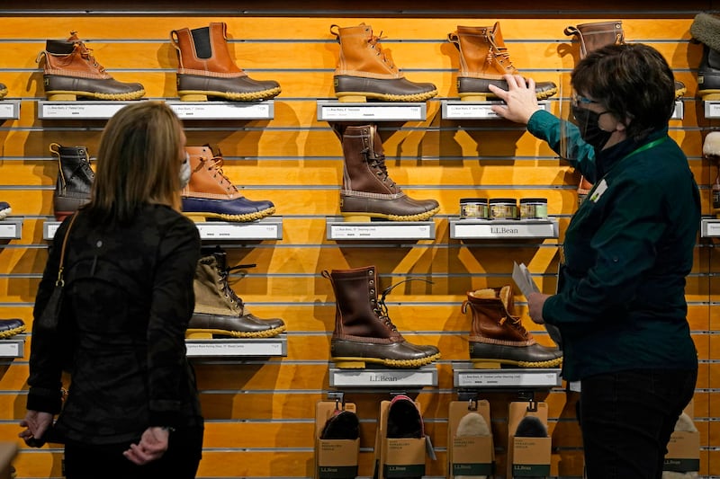 In this March 18, 2021 file photo, a salesperson helps a customer shopping for Bean Boots at the L.L. Bean flagship retail store in Freeport, Maine. Newly vaccinated and armed with $1,400 stimulus checks, Americans went on a spending spree last month, buying new clothes and going out to eat again.