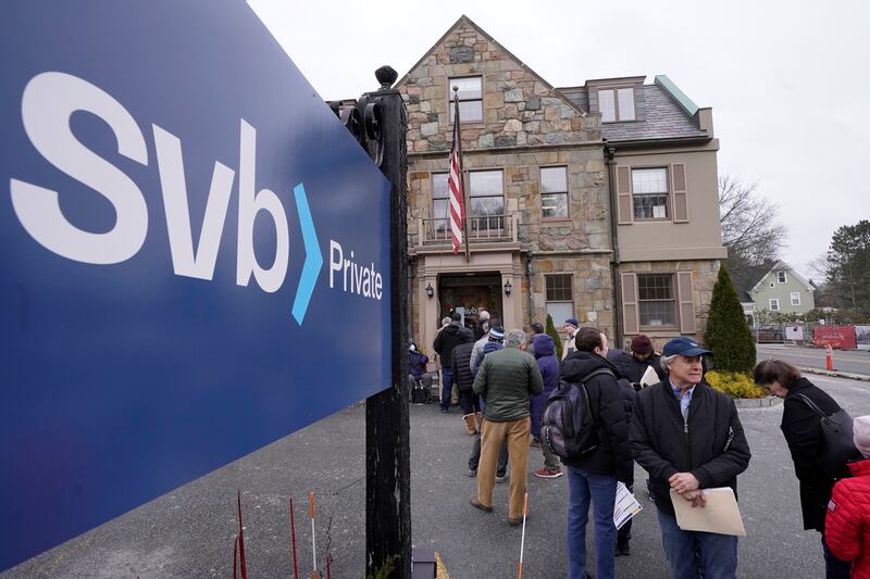 Customers and bystanders form a line outside a Silicon Valley Bank branch location in Wellesley, Mass.