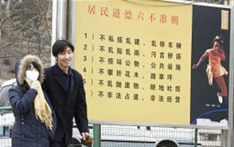 A couple walks past a board in Beijing with a list of things not to do.