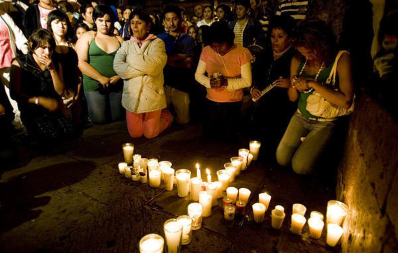 Residents of Morelia, Mexico, pray and light candles Tuesday at the site of a deadly Independence Day explosion Monday.