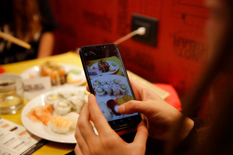 Customer Chiara Valenzano takes pictures of her dishes as she has lunch at This Is Not a Sushi Bar in Milan, Italy.