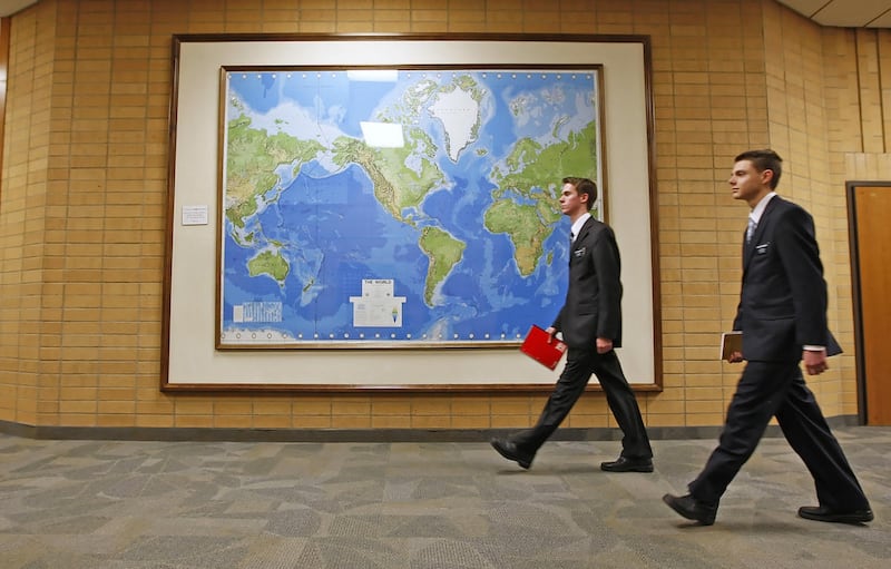FILE- In this Jan. 31, 2008, file photo, two Mormon missionaries walk past a large map of the world in a hallway at the Missionary Training Center in Provo, Utah. A secularist organization and a gay activist group delivered letters to the U.S. state and j