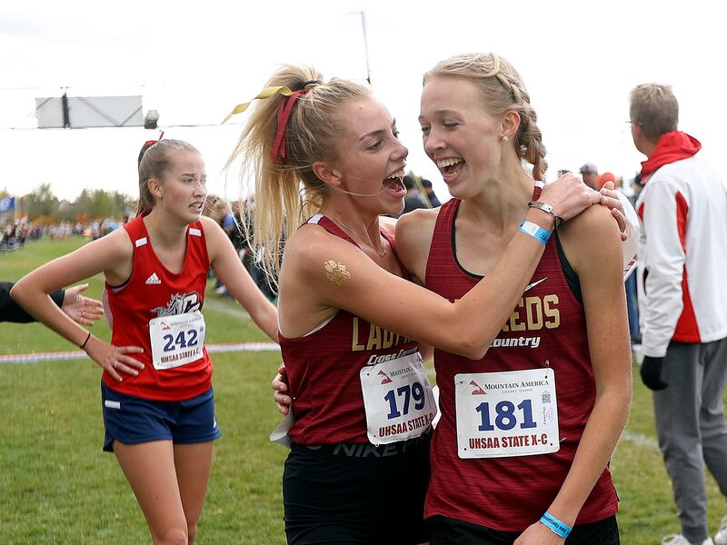 Cedar High’s Carissa Hofeling and Cedar High’s Emma Page celebrate their first and second place finishes in the 4A cross-country state championship