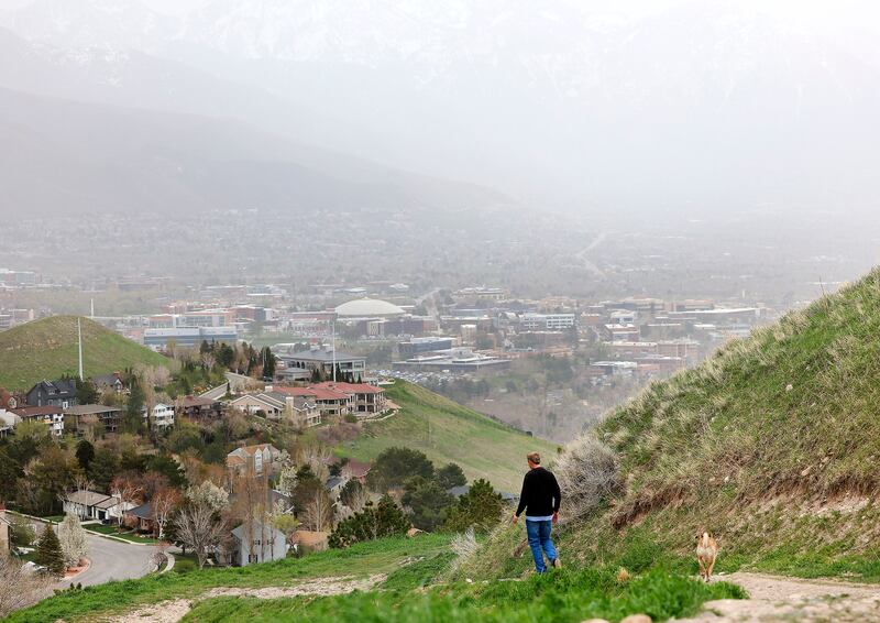 The Wasatch Mountains are barely visible on a windy day as a walker hikes in the foothills of Salt Lake City on April 21, 2022.
