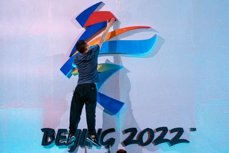 A crew member leaps to fix a logo for the 2022 Beijing Winter Olympics before a launch ceremony to reveal the motto.
