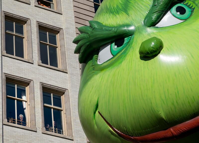 The Grinch balloon passes by windows of a building on Central Park West during Macy’s Thanksgiving Day Parade in New York, Nov. 23, 2017.