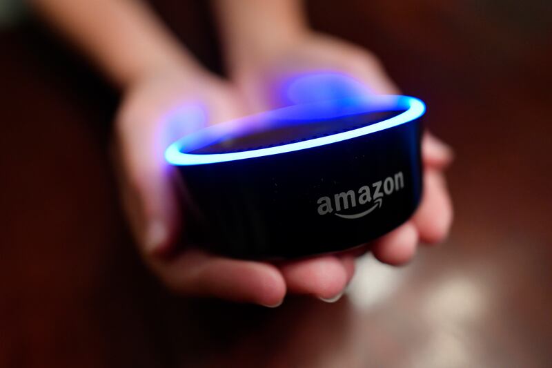 FILE - In this Aug. 16, 2018, file photo a child holds his Amazon Echo Dot in Kennesaw, Ga. Amazon met with skepticism from some privacy advocates and members of Congress last year when it introduced its first kid-oriented voice assistant , along with bri