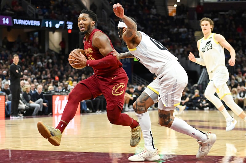 Cleveland Cavaliers guard Donovan Mitchell, wearing red, drives against Utah Jazz guard Jordan Clarkson during the second half of an NBA basketball game, Monday, Dec. 19, 2022, in Cleveland.