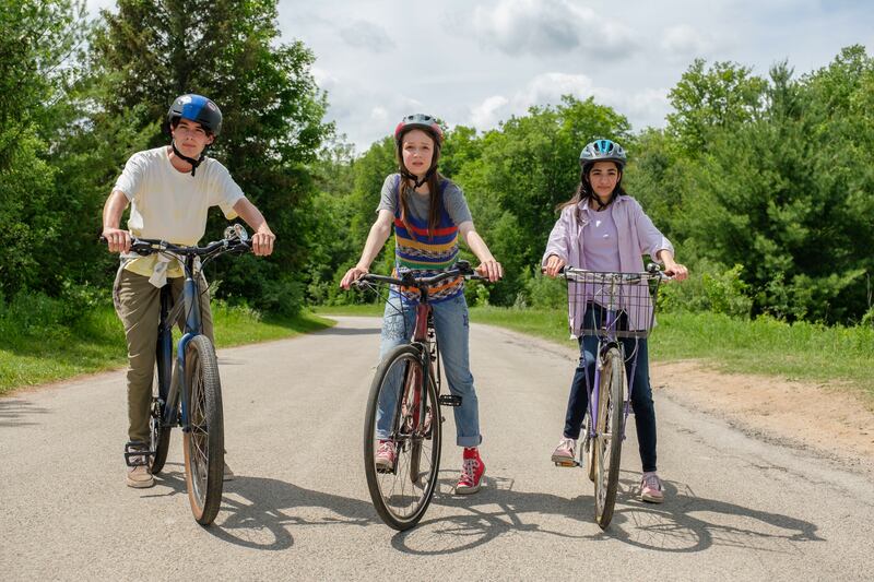 Ruby O’Reilly (Zoe Wiesenthal) with her friends Sam Price (Dylan Kingwell), left, and Mina Amani (Lina Sennia), right, on their bicycles.