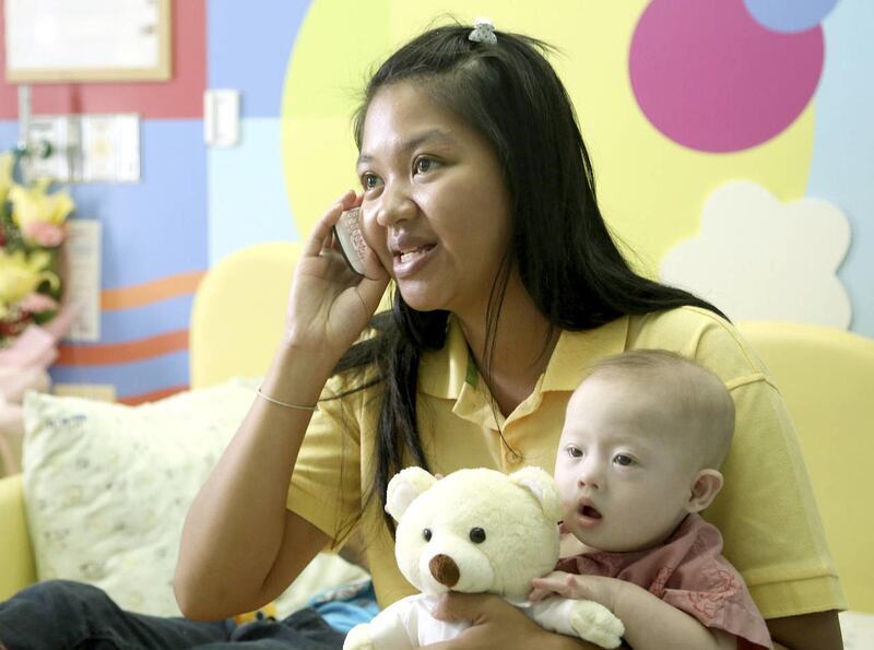Pattaramon Chanbua, 21, talks on a mobile phone while holding her son Gammy at a hospital in Chonburi province, southeastern Thailand Sunday, Aug. 3, 2014. The Australian government is consulting Thai authorities after news emerged that Gammy, a baby with