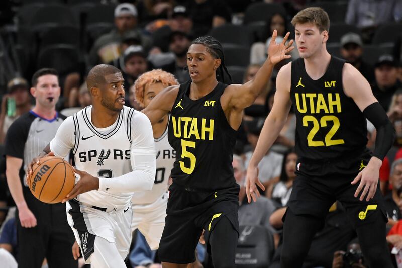 San Antonio Spurs guard Chris Paul (3) drives against Utah Jazz's Cody Williams (5) and Kyle Filipowski during game, Saturday, Oct. 12, 2024, in San Antonio.