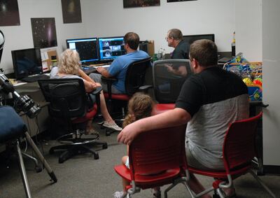 Rapt visitors examine photos as they come in from the Beaver County observatory. From left, back row (nearer the viewer) are Zoey Hinckley, 5, and her father, Spencer Hinckley, North Salt Lake; front row, Lana Carter, Kaysville; Paul Ricketts of the Unive