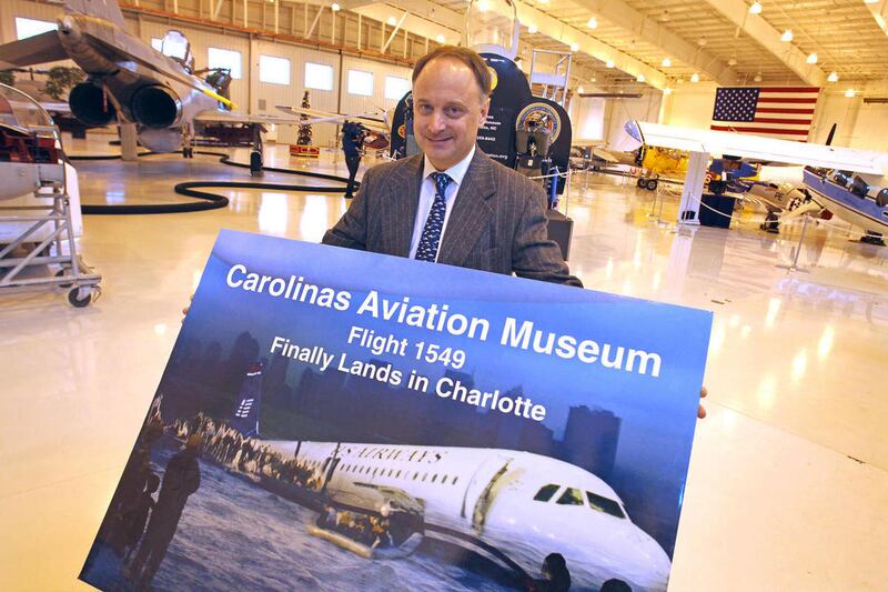 Shawn Dorsch, president of the Carolinas Aviation Museum, carries a poster Wednesday, Jan. 5, 2011, announcing the future arrival of the remains of the US Airways jet that crash landed safely on the Hudson River in 2009, to the Charlotte, N.C. museum. Fli