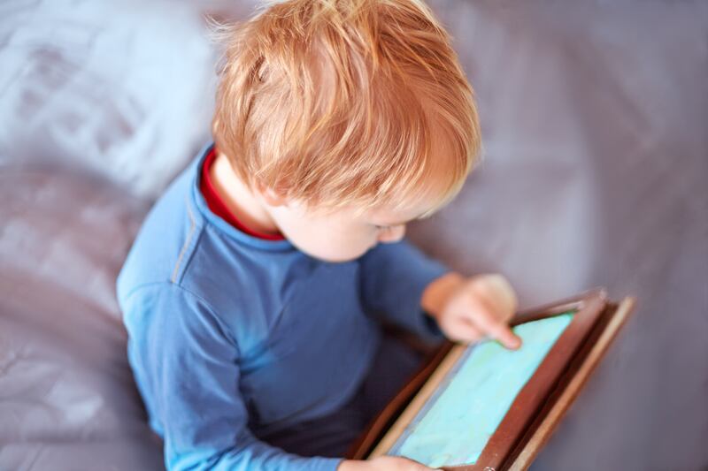 A young boy plays on a tablet.
