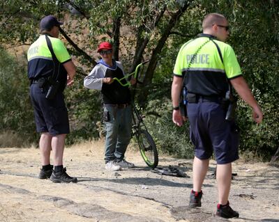 Salt Lake City police officers Chuck McNamee and Austin Gold talk to a person camping by the Jordan River in Salt Lake City on Tuesday, Aug. 14, 2018.