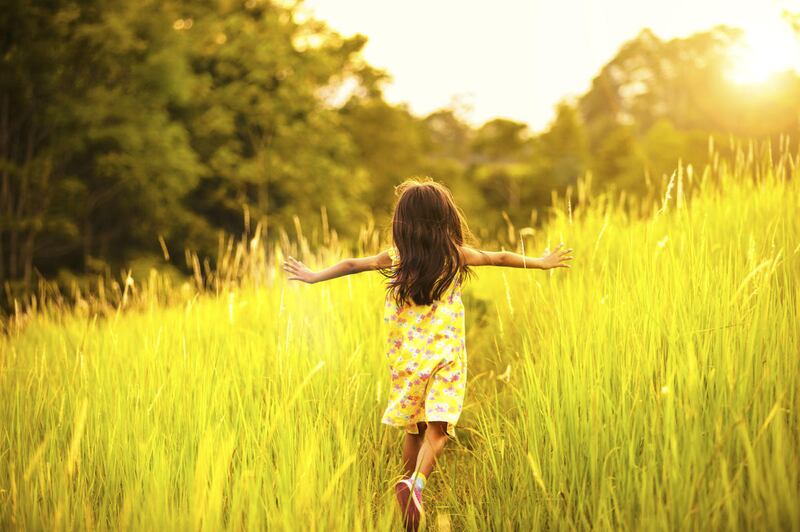 Little girl running on meadow with sunset