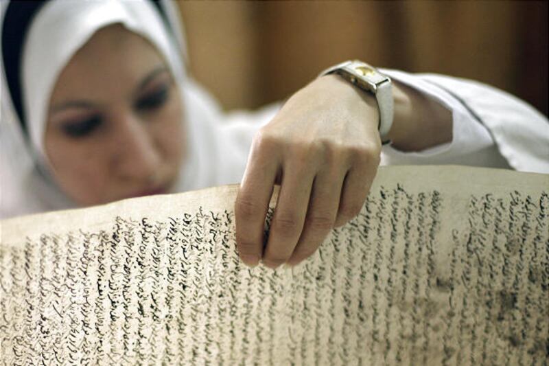 An employee of the Iraq National Library inspects a damaged document at the library in Baghdad. Saad Eskander, the library's director, is leading efforts to reclaim more materials.