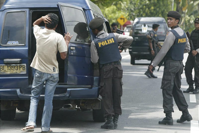 Indonesian police officers check a car during a search for militants in Pidie, Aceh province, Indonesia, Tuesday.