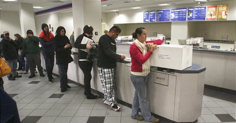 Postal customers wait in line to ship packages during the Christmas rush at the downtown post office.