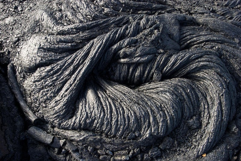 In this Monday, Aug. 8, 2016 photo, hardened lava rock from Kilauea, an active volcano on Hawaii's Big Island, is shown in Volcanoes National Park near Kalapana, Hawaii. The current lava flow erupted from a vent on the volcano in May and made its way to t
