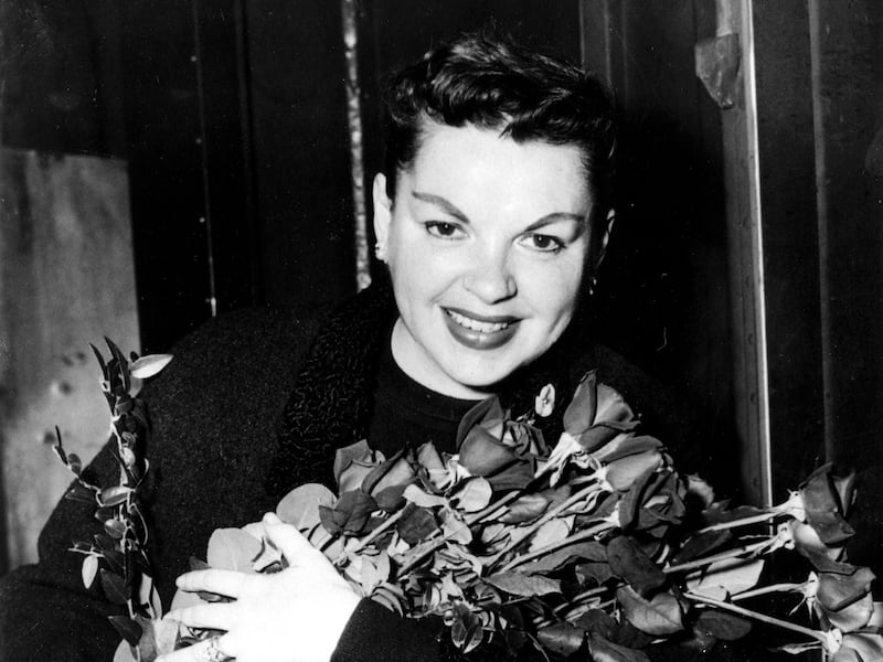 Judy Garland poses with long-stemmed roses in her arms as she arrives in New York City on Sept. 17, 1956.