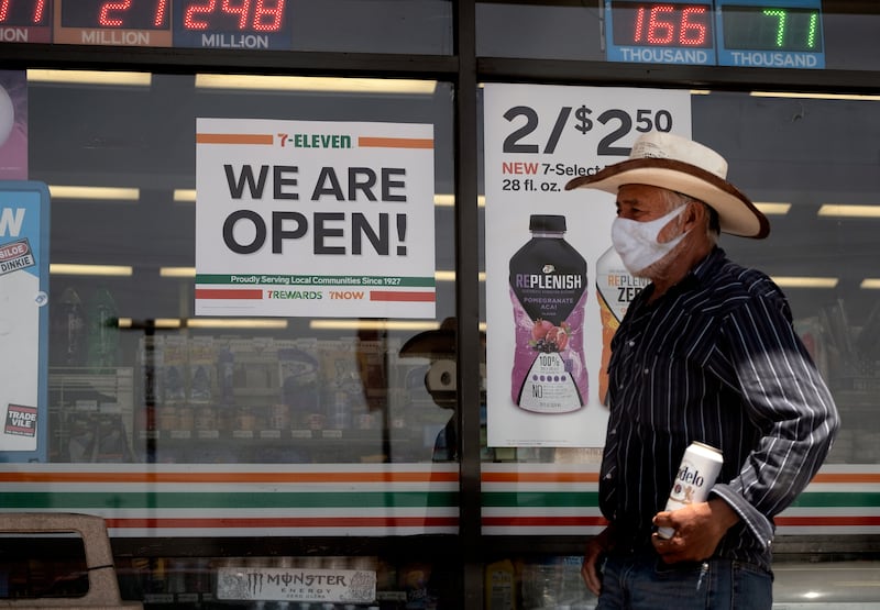 In this Sunday, May 10, 2020 photo a man wearing a protective mask from the coronavirus leaves a 7-Eleven store Los Angeles Calif. The most significant reopening of the California economy during the coronavirus pandemic started Friday with tens of thousands of businesses cleared to open with limitations.