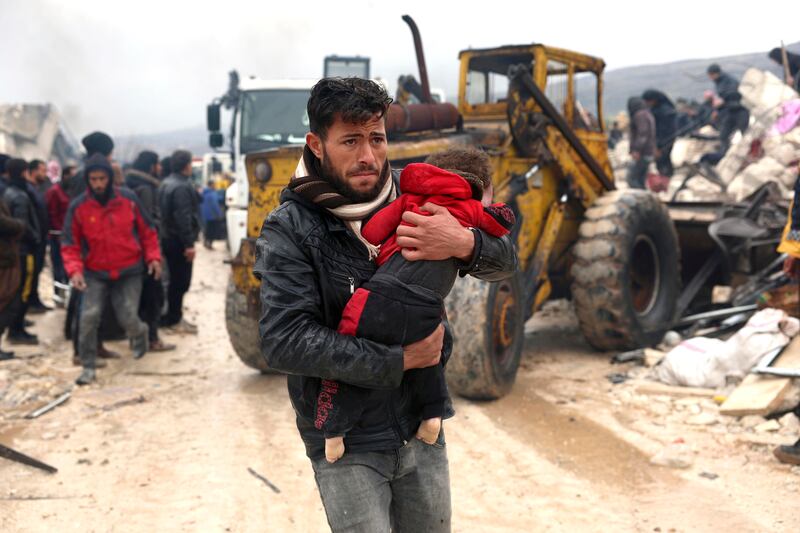 A man carries the body of an earthquake victim in the Besnia village near the Turkish border, Syria, Monday, Feb. 6, 2023.