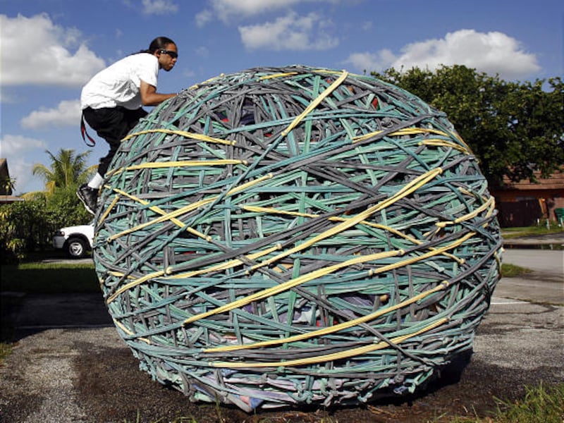 Joel Waul, 27, climbs on top of his rubber band ball in the driveway of his home in Lauderhill, Fla., last Friday.