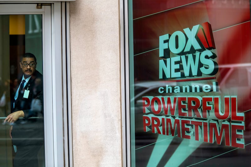 FILE - In this Wednesday, April 19, 2017, file photo, a security guard looks out of the the News Corp. headquarters in Midtown Manhattan, in New York. Disney announced Thursday, Dec. 14, 2017, that it is buying a large part of Fox, but Fox News Channel an