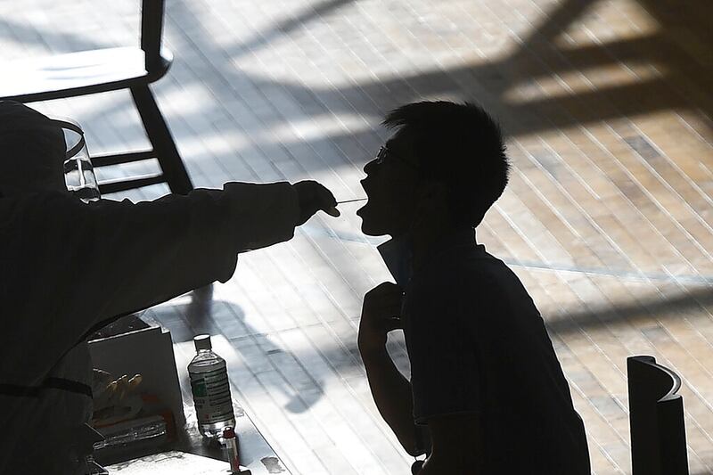 A medical worker takes a swab sample during a COVID-19 test in Wuhan.