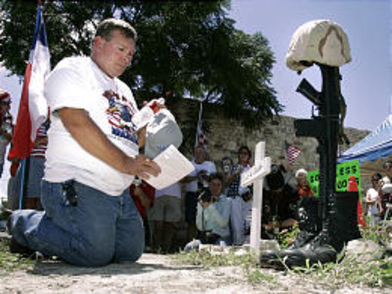 Gary Qualls, of Temple, Texas, kneels at a memorial to his fallen son, Marine Lance Cpl. Louis Wayne Qualls, in Crawford, Texas.