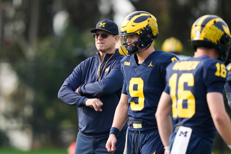 Michigan coach Jim Harbaugh, left, stands near quarterbacks J.J. McCarthy (9) and Davis Warren (16) during practice.