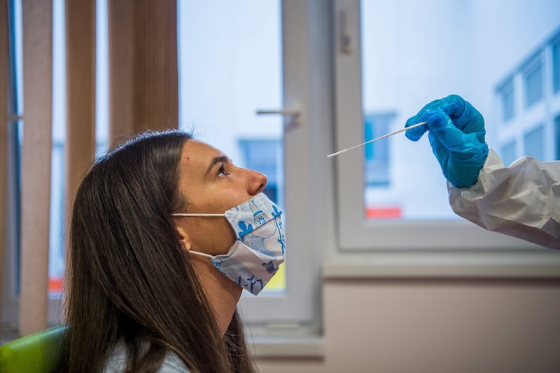 A medical student takes a nose swab sample for the novel coronavirus COVID-19 from a staff member of a kindergarten in Budapest, Hungary, during the national quick testing of Hungarian health, social, nursery, kindergarten workers and teachers Monday, Nov. 30, 2020.