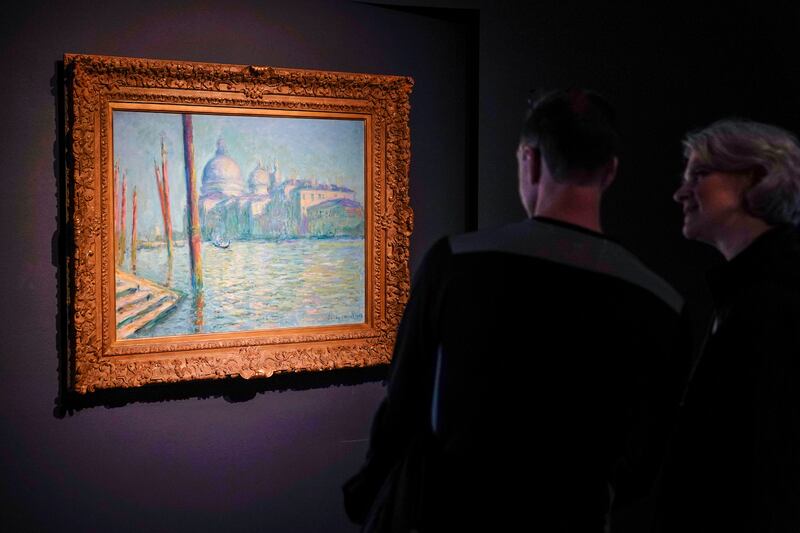 People look at a painting by Claude Monet at Sotheby’s in New York, Wednesday, May 11, 2022. On Sunday, Oct. 23, 2022, climate protesters threw mashed potatoes at a Monet painting at Museum Barberini in Germany.