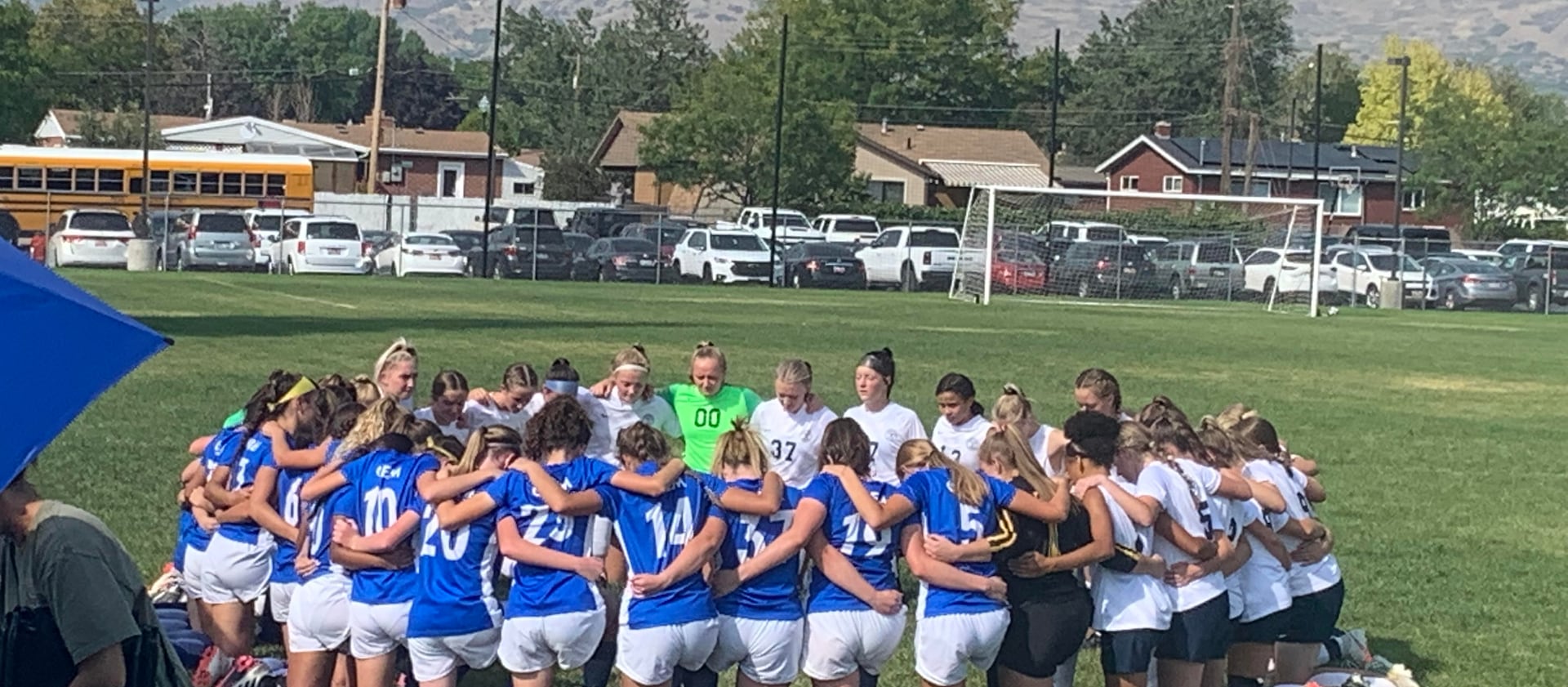 The Timpanogos High School varsity girls soccer team kneels in prayer with the opposing Orem High School team.