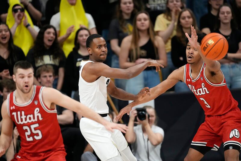 Colorado guard Jalen Gabbidon, center, passes the ball as Utah guard Rollie Worster, left, and forward Bostyn Holt defend in the first half of an NCAA college basketball game Saturday, March 4, 2023, in Boulder, Colo.