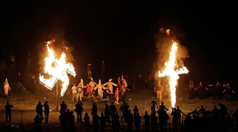 FILE - In this April 23, 2016 file photo, members of the Ku Klux Klan participate in cross and swastika burnings after a "white pride" rally in rural Paulding County near Cedar Town, Ga. Extremist groups are joining together with a shared goal for whites.