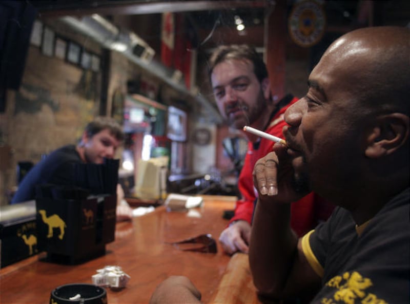 Shea McCloud, right, lights up a cigarette while chatting with Piper Down pub owner Dave Morris and Kyle Moore, left, on Tuesday in Salt Lake City.